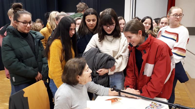 Eva Erben signing book with students
