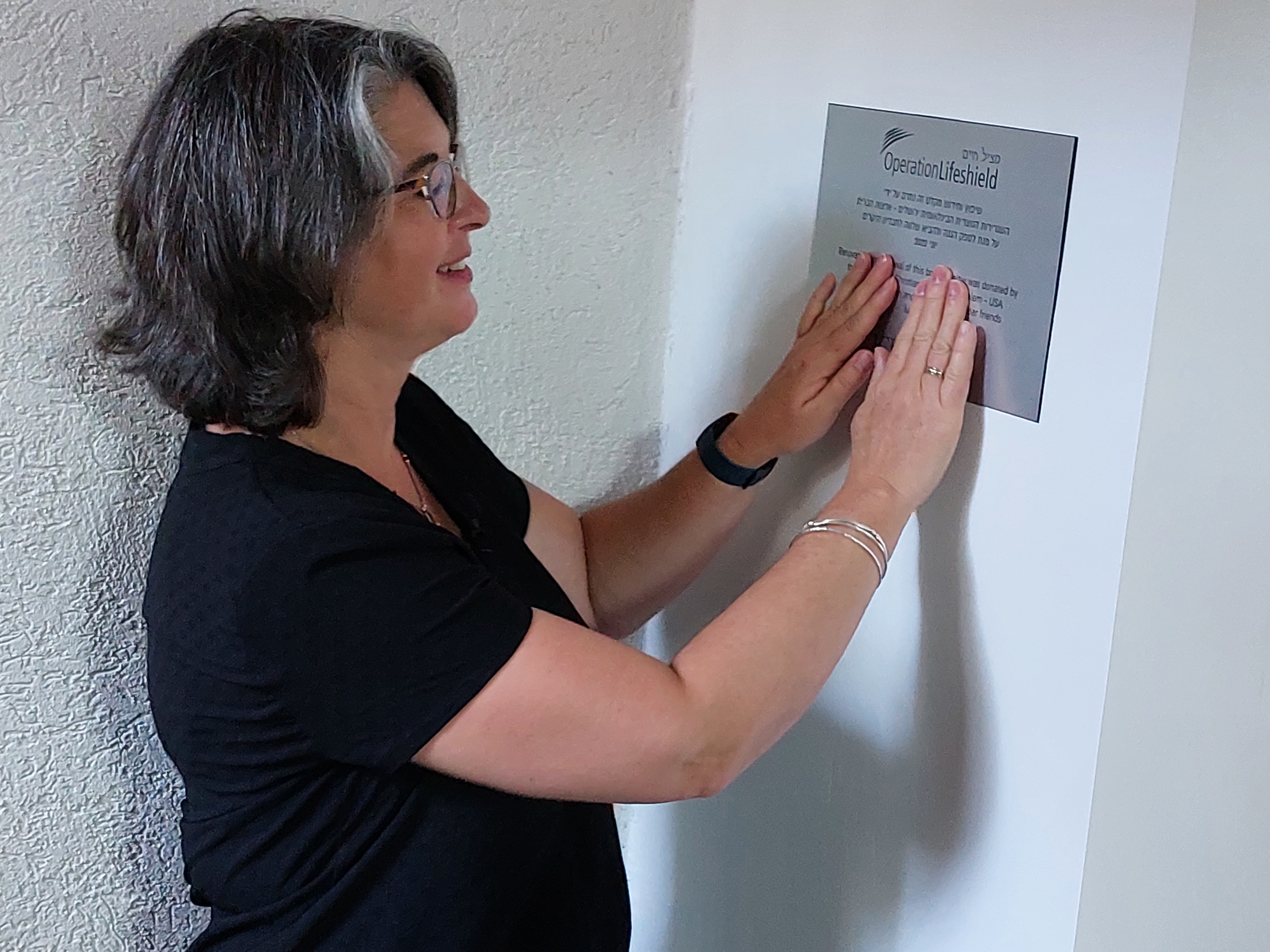Nicole sets plaque on the wall of the bomb shelter entrance