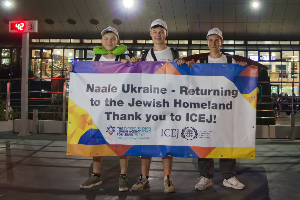 3 Jewish students hold a banner at Chisinau Airport, thanking ICEJ for their flight to Israel