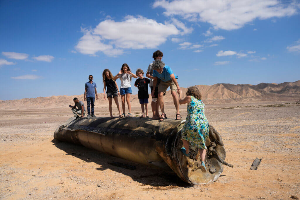 Local Arab and Jews stand on a spent Iranian missile fuselage in the Negev last year (AP photo)