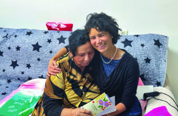 ICEJ Staff embrace a Jewish lady receiving a Passover gift.