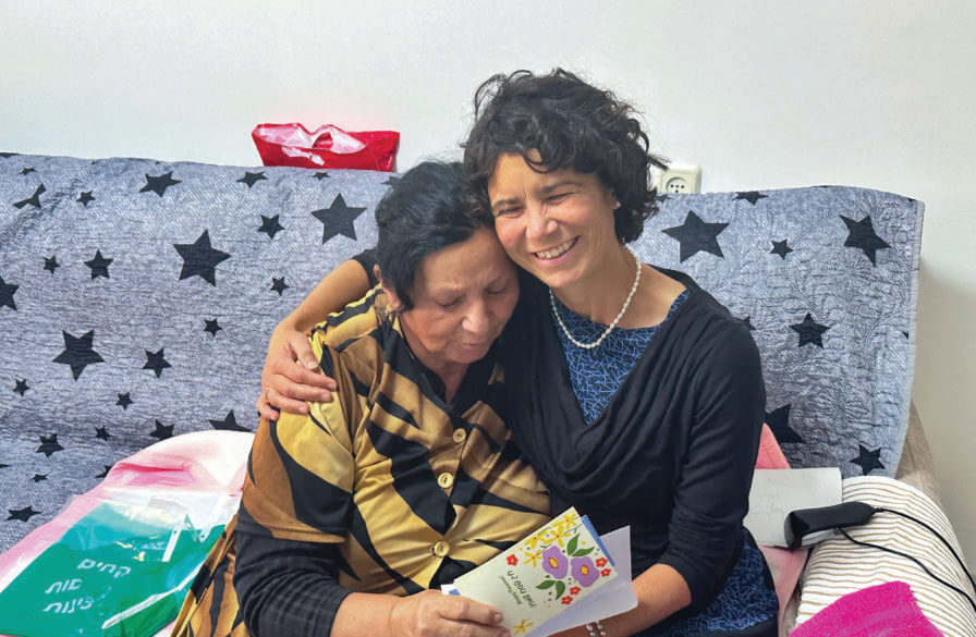 ICEJ Staff embrace a Jewish lady receiving a Passover gift.
